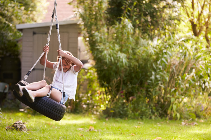 young-girl-playing-on-tire-swing-in-garden-PJQ4ZSN.jpg